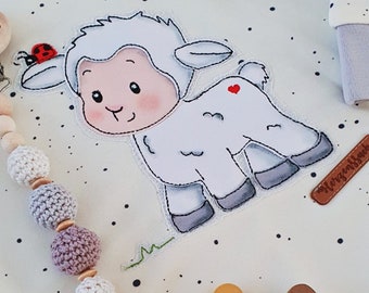 May include: A white baby onesie with a cute cartoon lamb applique. The onesie has a light blue collar and a white polka dot pattern. The onesie is paired with a wooden bead and crocheted ball teether and a pacifier.