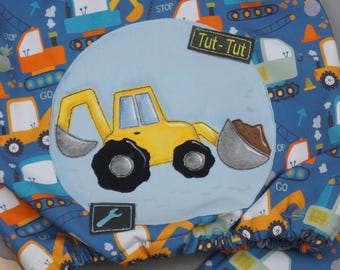 May include: A blue fabric with a yellow excavator applique. The excavator has a brown dirt scoop and the words "Tut-Tut" are on the fabric. The fabric is covered in a pattern of construction vehicles and the words "Go" and "Stop".