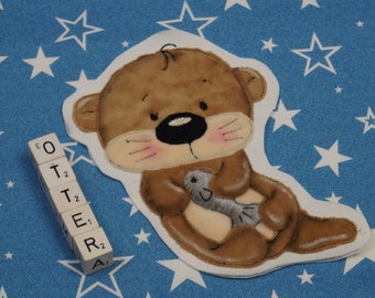 May include: A brown and white plush otter holding a gray fish. The otter is surrounded by white stars on a blue background. The word "OTTER" is spelled out with letter tiles.