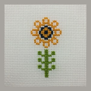 May include: A cross-stitch pattern of a yellow sunflower with a black center and green stem and leaves.