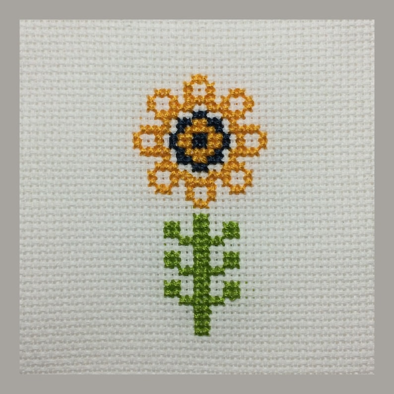 May include: A cross-stitch pattern of a yellow sunflower with a black center and green stem and leaves.