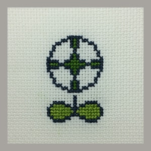 May include: A white cross-stitch embroidery of a green flower with a dark blue outline.