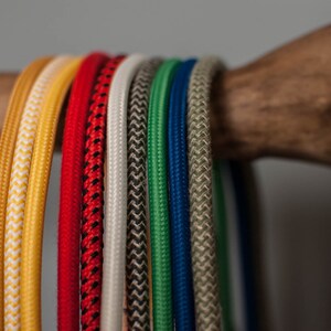 May include: A collection of colorful braided cords in various colors, including yellow, red, white, black, green, blue, and beige.