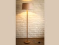 Modern wooden floor lamp in oak and beech with linen lampshade, cylindrical design.