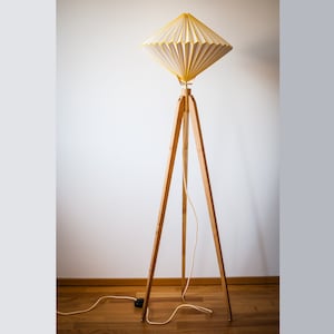 May include: A white and yellow floor lamp with a triangular base and a pleated fabric shade.