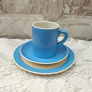 Könnte beinhalten: Ein blaues Keramik-Teetassen-Set. Tasse und Untertasse haben einen weißen Rand.
