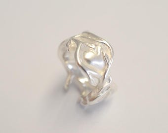Op de afbeelding: Een zilveren ring met een hartvormig ontwerp. De ring is gemaakt van een delicaat, ingewikkeld patroon van verweven takken.