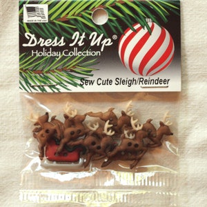 Può includere: Un pacchetto di bottoni marroni a forma di renna e slitta con la scritta "Dress It Up Holiday Collection Sew Cute Sleigh/Reindeer" sul davanti.