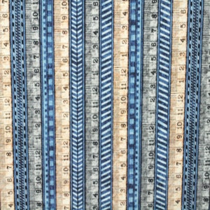 Könnte beinhalten: Stoff mit Lineal-Design. Das Muster zeigt vertikale Streifen von Linealen in Blau-, Grau- und Beigetönen. Jedes Lineal ist mit Zahlen von 1 bis 12 Zoll (ca. 30 cm) markiert und erzeugt ein sich wiederholendes Muster.