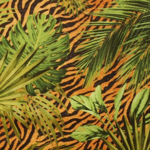 Könnte beinhalten: Nahaufnahme eines Stoffes mit Tigerstreifenmuster. Der Stoff ist orange und schwarz mit grünen Blättern bedruckt.