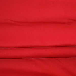Könnte beinhalten: Ein einfarbiger roter Stoff mit glatter Textur. Der Stoff ist dreifach gefaltet und bildet so eine Reihe horizontaler Linien.