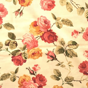 Könnte beinhalten: Ein cremefarbener Stoff mit einem sich wiederholenden Muster aus rosa, gelben und roten Rosen. Die Rosen sind stilisiert und haben einen Vintage-Look.