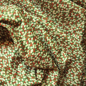 Op de afbeelding: Groene stof met een wit en rood bloemenpatroon. De stof is gevouwen en heeft een textuur.