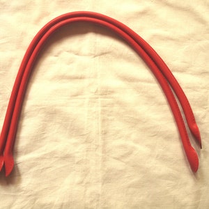 Pode incluir: Duas correias de couro vermelho para uma bolsa de mão ou carteira.