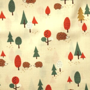 Può includere: Un tessuto color crema con un motivo ripetitivo di alberi e ricci stilizzati. Gli alberi sono in tonalità di verde, rosso e marrone. I ricci sono marroni con accenti bianchi.