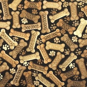 Op de afbeelding: Een zwarte stof met een herhalend patroon van bruine, botvormige hondenkoekjes met de tekst "Good Dog" erop gedrukt.
