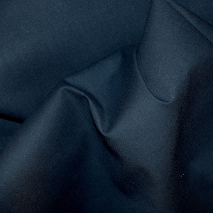 Pode incluir: Um close-up de um tecido azul escuro com uma textura lisa. O tecido está dobrado e drapeado, criando dobras suaves e sombras.