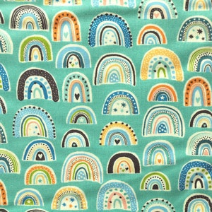 Peut inclure: Un tissu turquoise avec un motif répétitif d'arcs-en-ciel colorés. Les arcs-en-ciel sont décorés d'étoiles, de cœurs et de points.