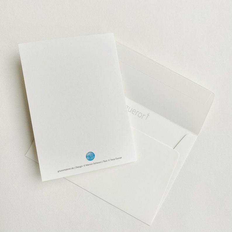 May include: A white envelope with a white card inside. The card has a blue circle with a design of a building on it. The text on the card reads "grussatelier.de | Design: &copy; Marion Schwarz | Text: &copy; Tanja Sassor".