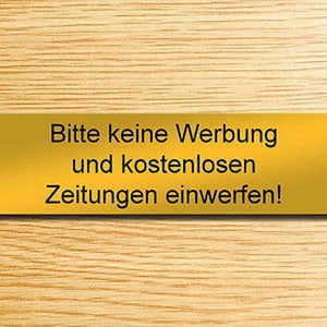 Op de afbeelding: Een gouden metalen bord met zwarte tekst die "Bitte keine Werbung und kostenlosen Zeitungen einwerfen!" zegt, wat vertaald wordt als "Gooi geen reclame en gratis kranten weg!"