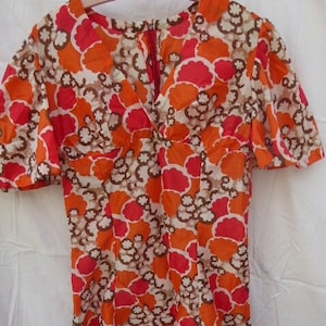 May include: A short-sleeved dress with a V-neckline and a floral print in shades of orange, red, and brown.