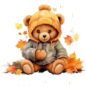 Op de afbeelding: Een bruine teddybeer met een gele gebreide muts en een blauw jasje zit op een bed van herfstbladeren.