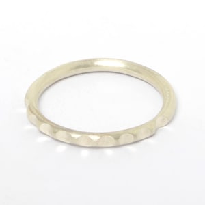 Könnte beinhalten: Ein schlichter Silberring mit einer Reihe kleiner, erhabener Punkte um das Band.