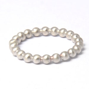 Könnte beinhalten: Ein silberner Ring aus kleinen, runden Perlen.