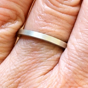 Könnte beinhalten: Ein schlichter Silberring, der an einem Finger getragen wird.