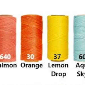 K&ouml;nnte beinhalten: Vier Garnrollen in verschiedenen Farben: Lachs, Orange, Zitronentropfen und Aquablau. Die Rollen sind mit ihren Farbnamen und Nummern beschriftet: 640, 30, 37 und 605.