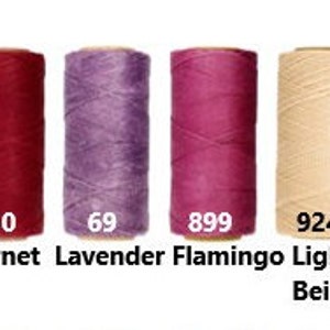 K&ouml;nnte beinhalten: Vier Garnrollen in verschiedenen Farben: Granatrot, Lavendel, Flamingorosa und Hellbeige. Die Rollen sind mit den Nummern 50, 69, 899 und 924 beschriftet.