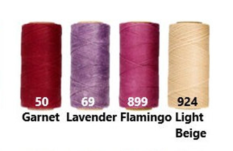 K&ouml;nnte beinhalten: Vier Garnrollen in verschiedenen Farben: Granatrot, Lavendel, Flamingorosa und Hellbeige. Die Rollen sind mit den Nummern 50, 69, 899 und 924 beschriftet.