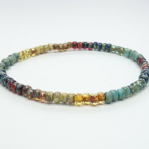 Peut inclure: Un bracelet en perles multicolores avec un dégradé de couleurs allant du bleu au jaune. Le bracelet est composé de petites perles rondes.