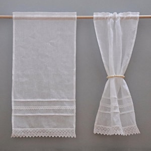 Peut inclure: Deux rideaux en lin blanc transparent suspendus &agrave; une tringle en bois. L'un est enti&egrave;rement d&eacute;ploy&eacute;, avec une bordure en dentelle d&eacute;taill&eacute;e en bas et des bandes de dentelle horizontales. L'autre est nou&eacute; avec un anneau clair.