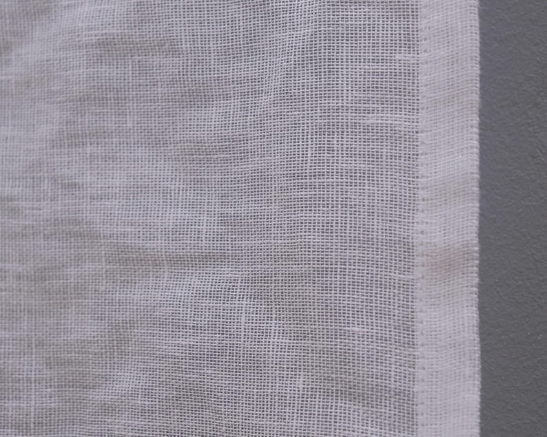 Peut inclure: Gros plan sur un tissu blanc, tiss&eacute; l&acirc;chement. Le tissu pr&eacute;sente un motif quadrill&eacute; et un aspect l&eacute;g&egrave;rement textur&eacute;. Une bordure blanche et propre longe le bord droit du tissu.