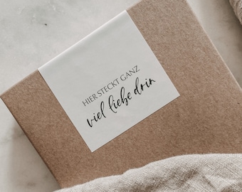 Puede incluir: Una caja de cartón marrón con una etiqueta blanca que dice "Hier steckt ganz viel liebe drin".