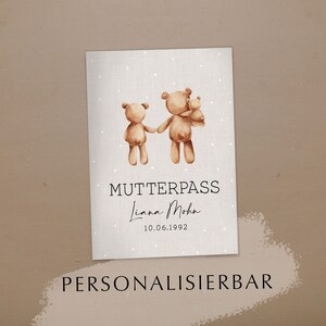 Könnte beinhalten: Eine druckbare Karte mit hellgrauem Hintergrund und weißen Punkten. Zwei braune Teddybären halten sich an den Händen. Der Text "MUTTERPASS" ist in Schwarz, gefolgt vom Namen "Liana Mohn" in Kursivschrift und dem Datum "10.06.1992". Der Text "PERSONALISIERBAR" ist in Schwarz am unteren Rand der Karte.