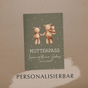Könnte beinhalten: Eine grüne Karte mit zwei braunen Teddybären, die sich an den Händen halten. Die Karte trägt die Aufschrift "Mutterpass" und "Liane Alicia Johns" mit dem Datum "18.03.1996". Die Karte trägt auch die Aufschrift "Personalisierbar" am unteren Rand.