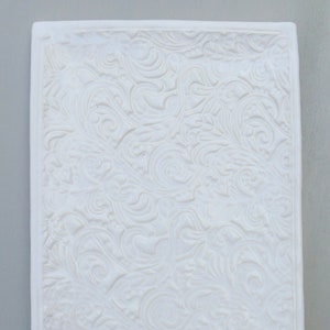 Peut inclure: Plateau rectangulaire en céramique blanche avec un motif floral en relief.