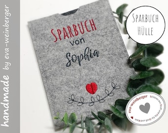 Può includere: Copertina per Sparbuch (libretto di risparmio) in feltro grigio con testo ricamato in rosso "Sparbuch von Sophia" e un cuore rosso con foglie verdi.
