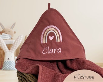 Könnte beinhalten: Ein burgunderfarbenes Kapuzenhandtuch mit einer Regenbogen- und Herzstickerei. Der Name "Clara" ist unter dem Regenbogen gestickt.