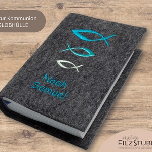 May include: Gray felt book cover with embroidered blue and white fish and the names Noah Samuel. The cover is for a communion gift.