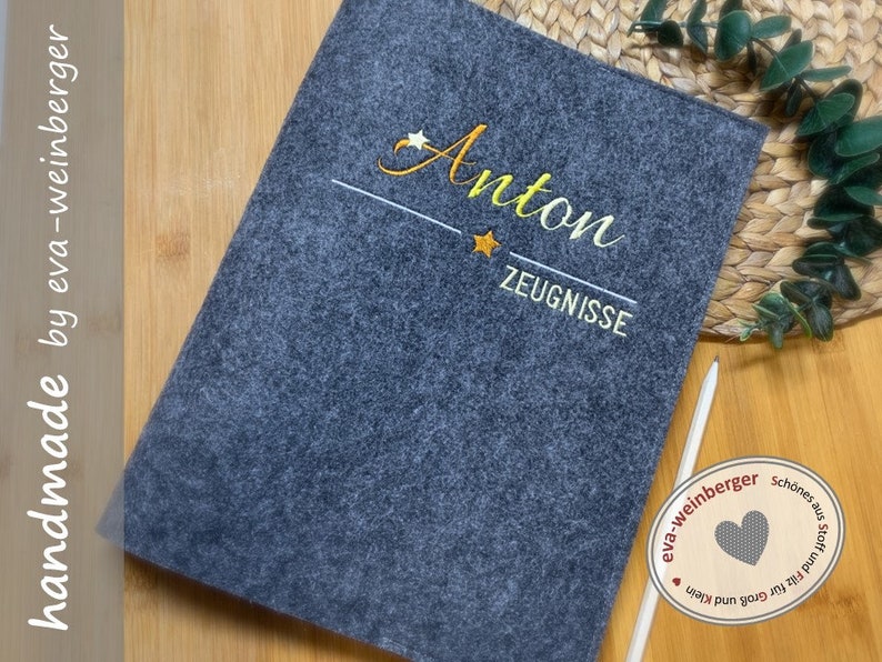 May include: A grey felt folder with the name "Anton" embroidered in yellow thread. The folder also has the word "Zeugnisse" embroidered in yellow thread. The folder is handmade by eva-weinberger.