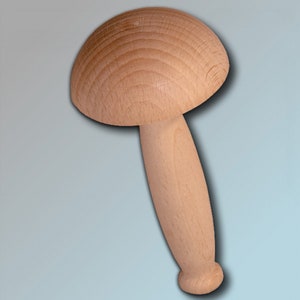 Może przedstawiać: Drewniany gałka w kształcie grzyba z gładkim, jasnobrązowym wykończeniem. Gałka ma zaokrąglony wierzchołek i długi, smukły trzonek.