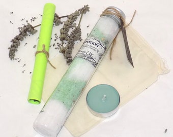 May include: A glass tube filled with white and green bath salts, a small teal candle, a rolled up green paper, and a small white cloth bag with a brown twine tie.