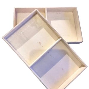May include: A white cardboard box with two compartments. The box is open and the compartments are empty.