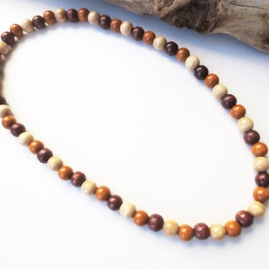 May include: A brown, beige, and cream colored wooden bead necklace. The beads are round and strung together on a cord.