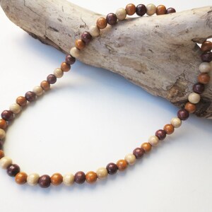 May include: A necklace made of brown, beige, and burgundy wooden beads. The beads are round and have a natural, polished finish.