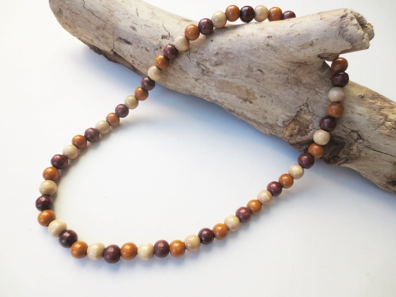 May include: A necklace made of brown, beige, and burgundy wooden beads. The beads are round and have a natural, polished finish.