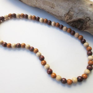 May include: A brown, beige, and cream wooden bead necklace. The beads are round and have a natural wood finish.